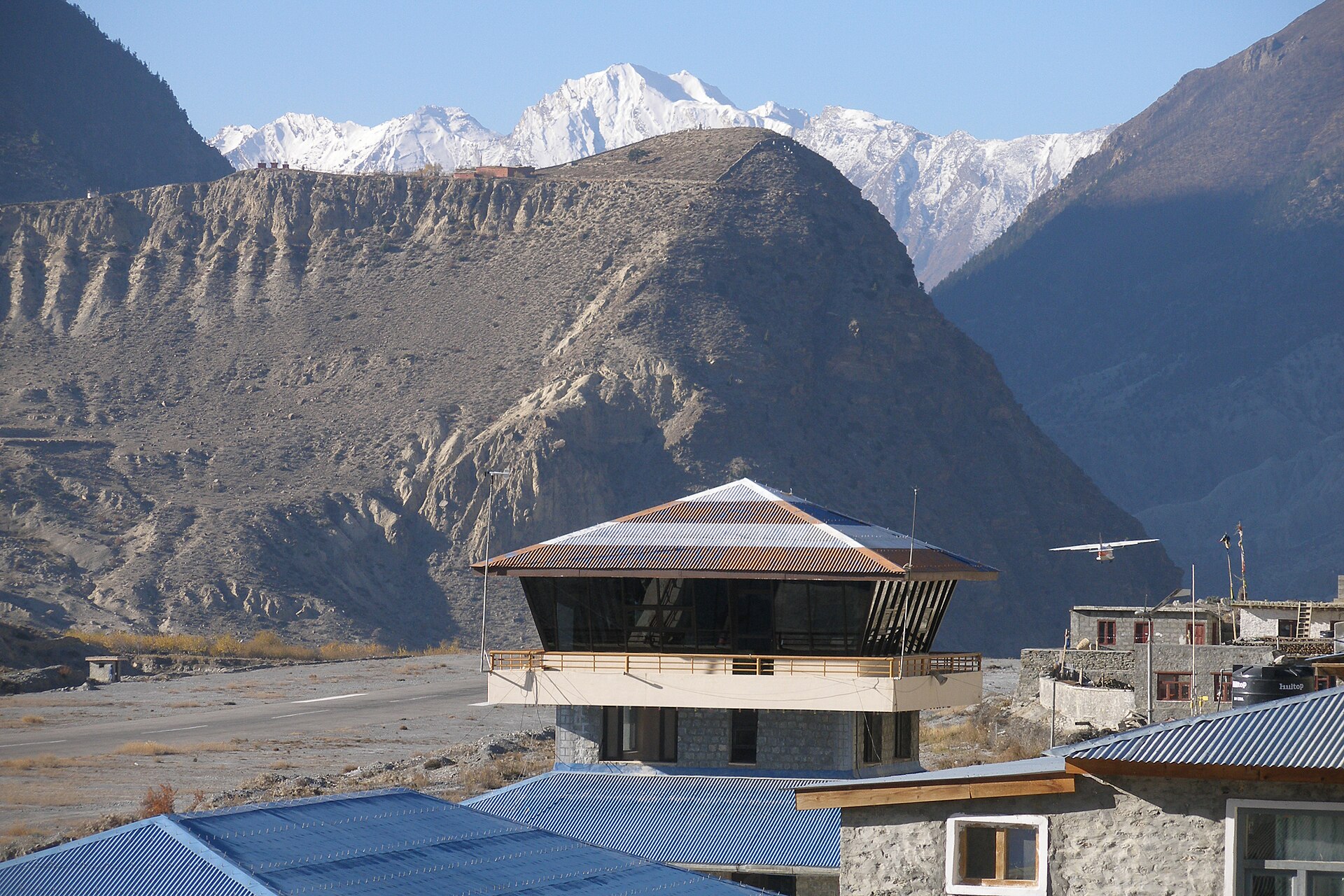 A small plane landing at Jomsom airstrip beneath snow-capped peaks